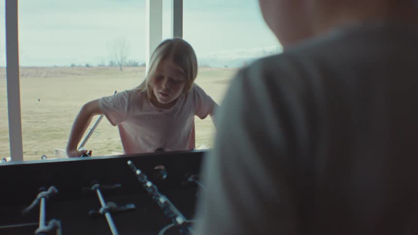 A brother and sister playing foosball in a house