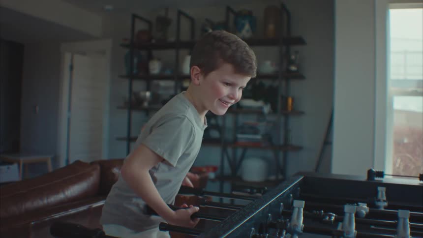 Little boy in a room playing foosball and having fun