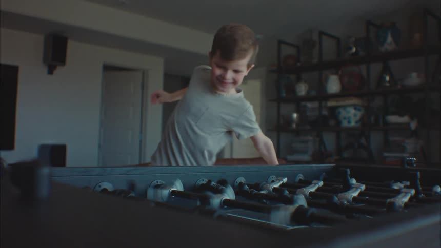 A little boy is having fun and smiling while playing foosball