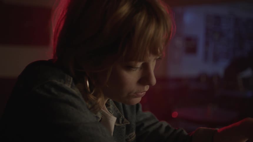 Solemn looking woman looking at her drink while sitting at a bar
