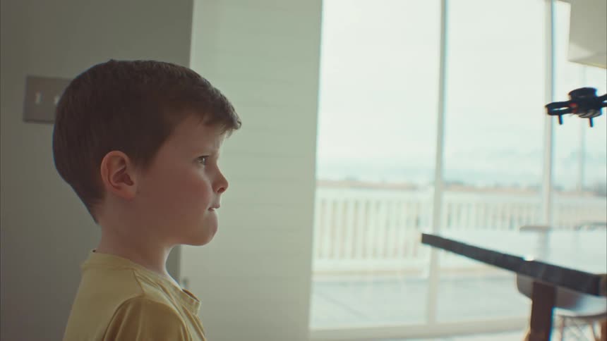 A boy has to dodge a remote controlled toy plane in a house