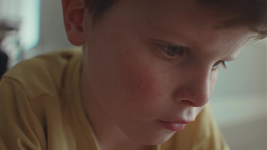 A young boy lying down on the floor looking focused