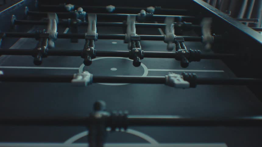 Closeup of a foosball table with people playing