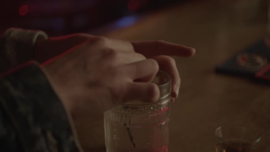 A woman sitting at a bar is fidgeting with her drink