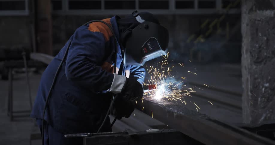 Man wearing welding equipment welding iron