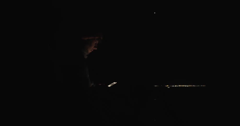 A mans face is illuminated by his phone in the dark of night