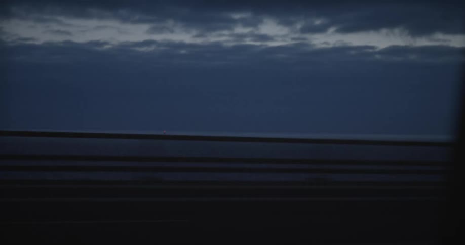 Far away coastline seen from a moving vehicle at evening