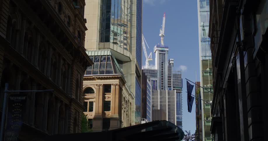 Multiple construction cranes build skyscraper at end of city street
