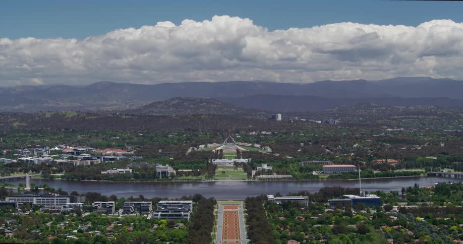 Aerial panorama of a city with a sea canal and surrounding mountain ranges on a cloudy day