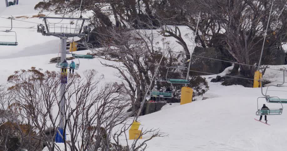 Skiers riding ski lift pass by skiers skiing on snowy slopes
