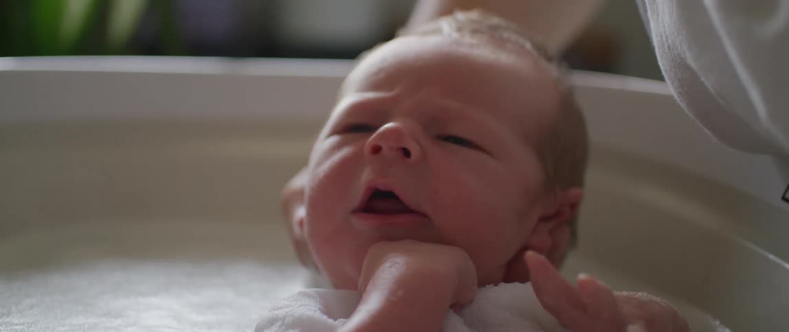 Portrait of a newborn baby taking a bath