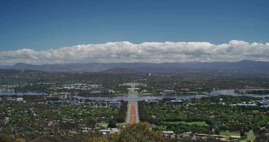 Panorama of a city on hills with vegetation and river channels on a blue sky day with clouds