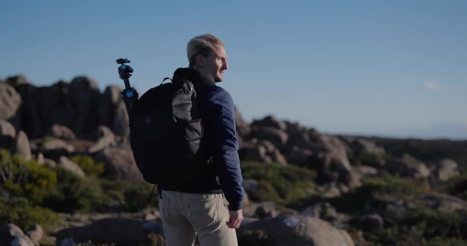 Man hiking in a natural environment with vegetation and rocks on a blue sky day