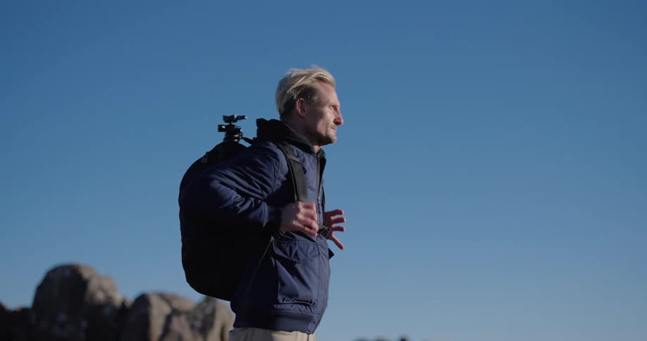 Man in a jacket and a backpack and a natural environment on a cloudless blue sky day