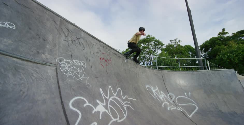 Man performing a trick with roller skates on the corner of a skate park