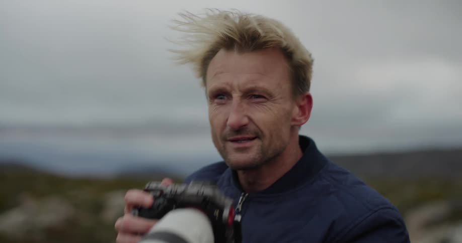 Man using his professional camera with a zoom in an outdoor environment with a wind
