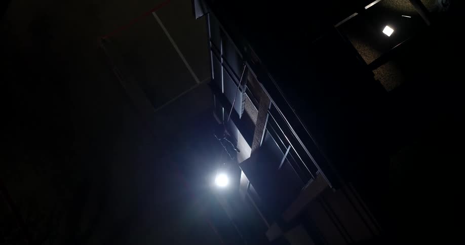 Person with a seat belt walking down the outside of a building at night
