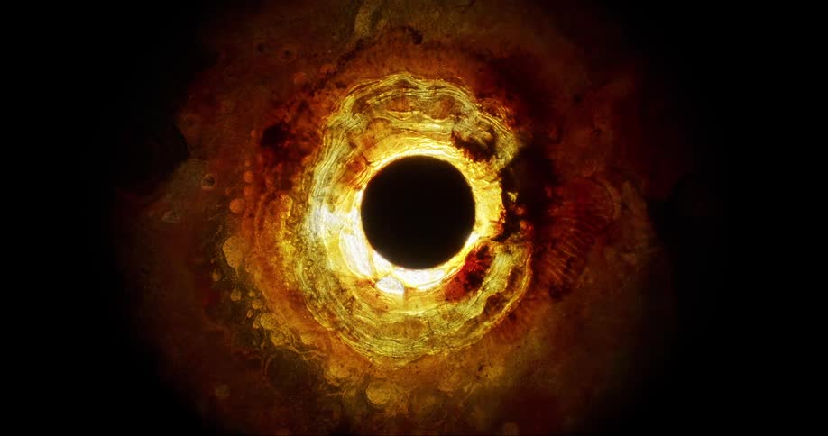 Rippling layers of glowing yellow and orange substance move around a deep black orb
