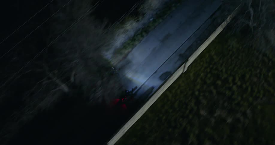 Two motorcyclists ride through residential neighborhood at night