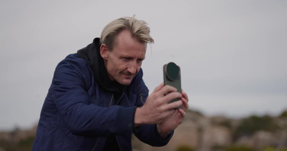 A man takes photos of plants in nature with a smartphone