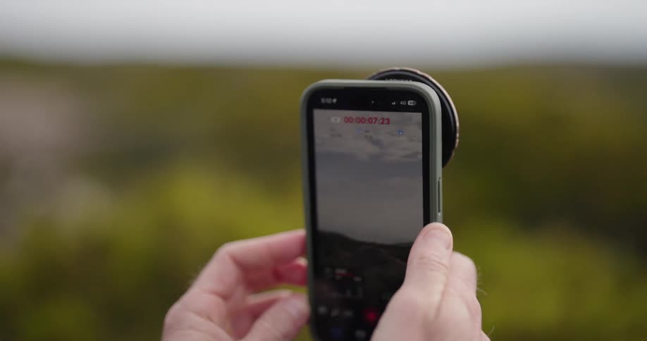Two hands hold a smart phone recording outdoor scene