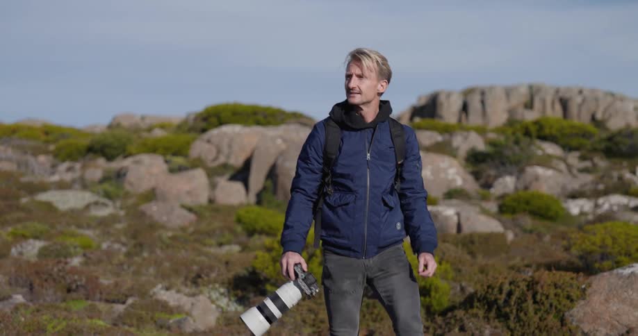 A man is hiking while carrying a large camera