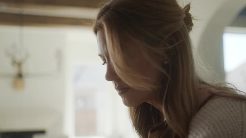 Blonde woman indoors looking down in a concentrated manner