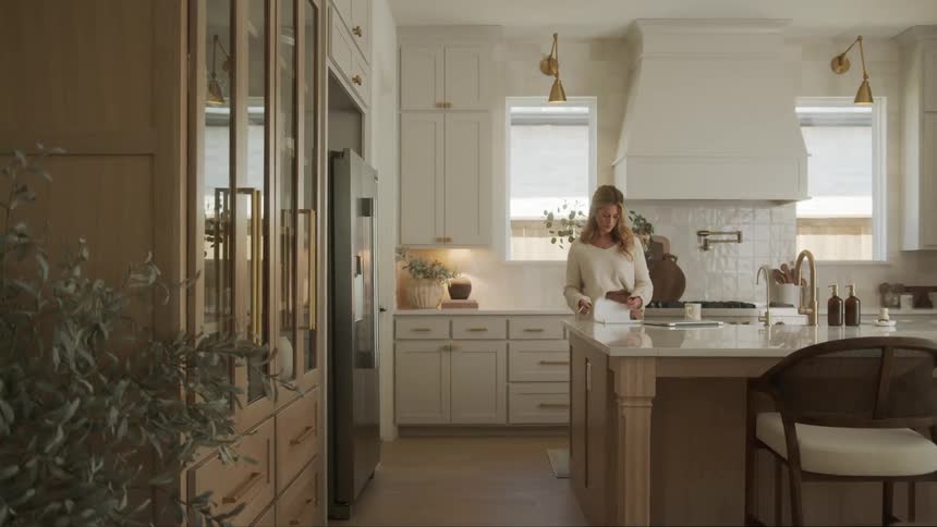 Woman in the kitchen at home opening her laptop during the day