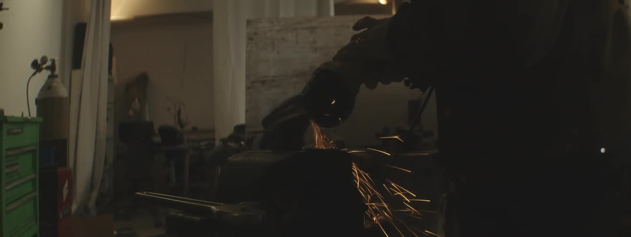 A worker grinds a piece of metal