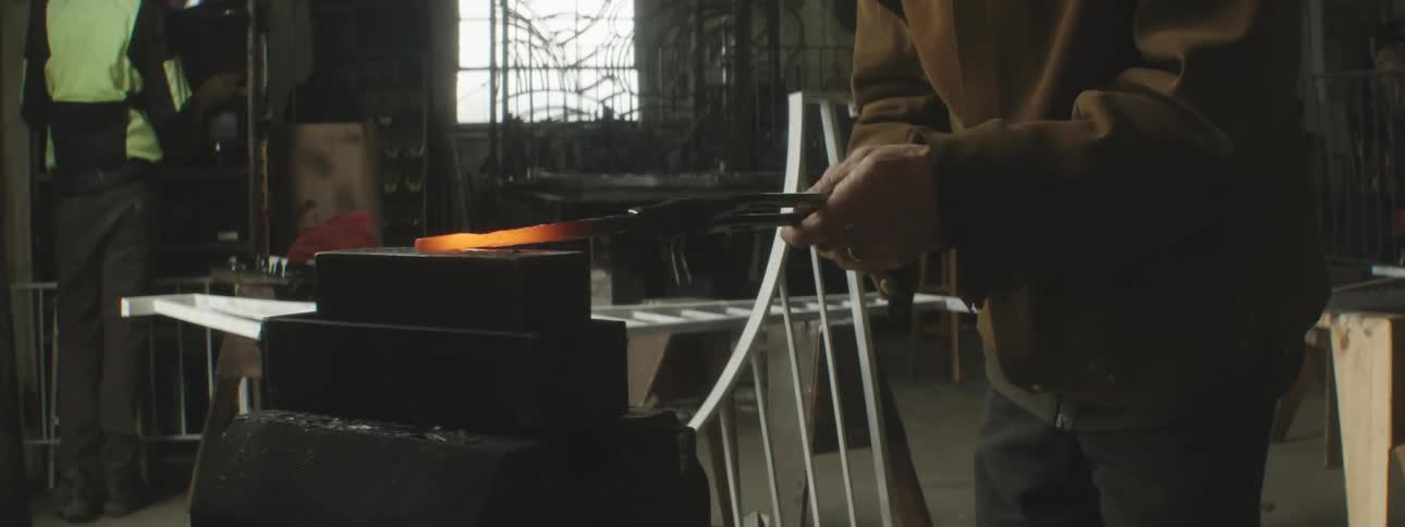 Hands of a man generating an iron rod in a metallurgical forging machine