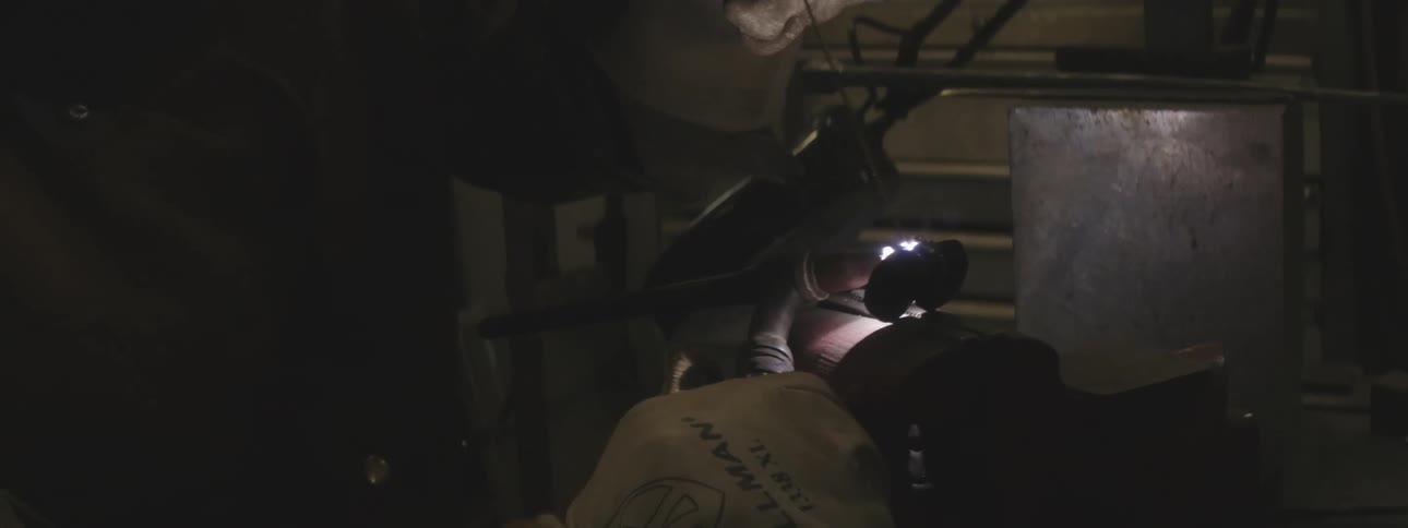 Concentrated metalworker man performing welding in detail