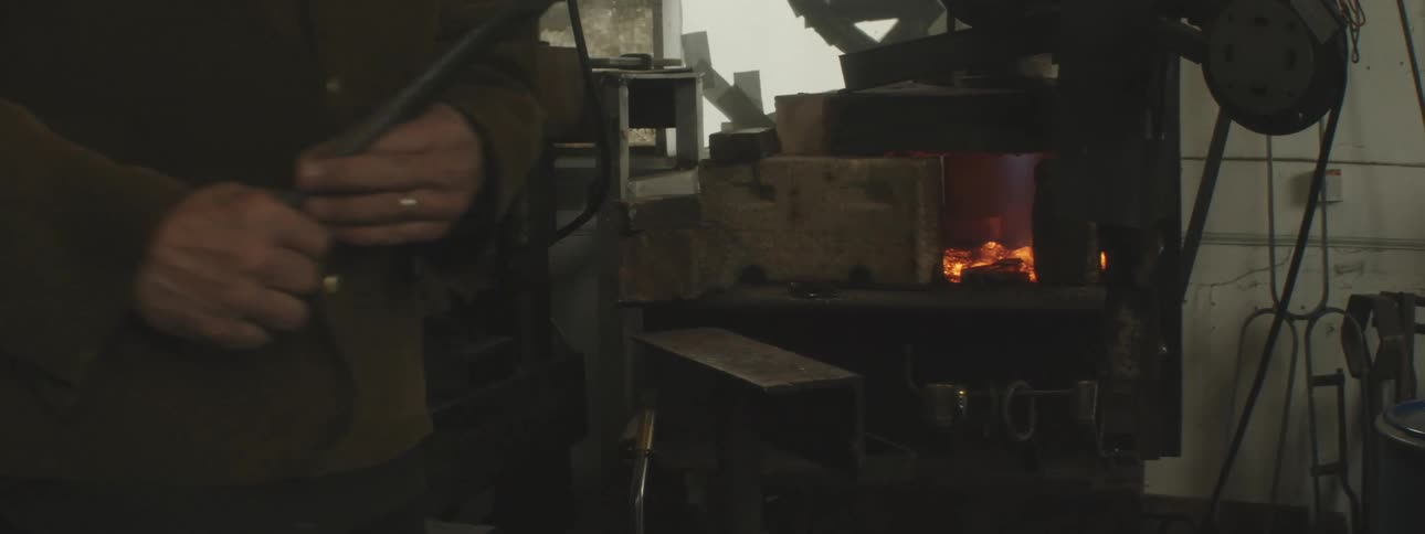Man placing a small steel plate on the coals and removing it