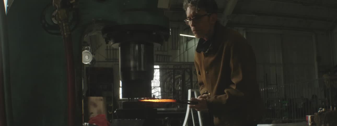 A man is hammering hot metal with the machine