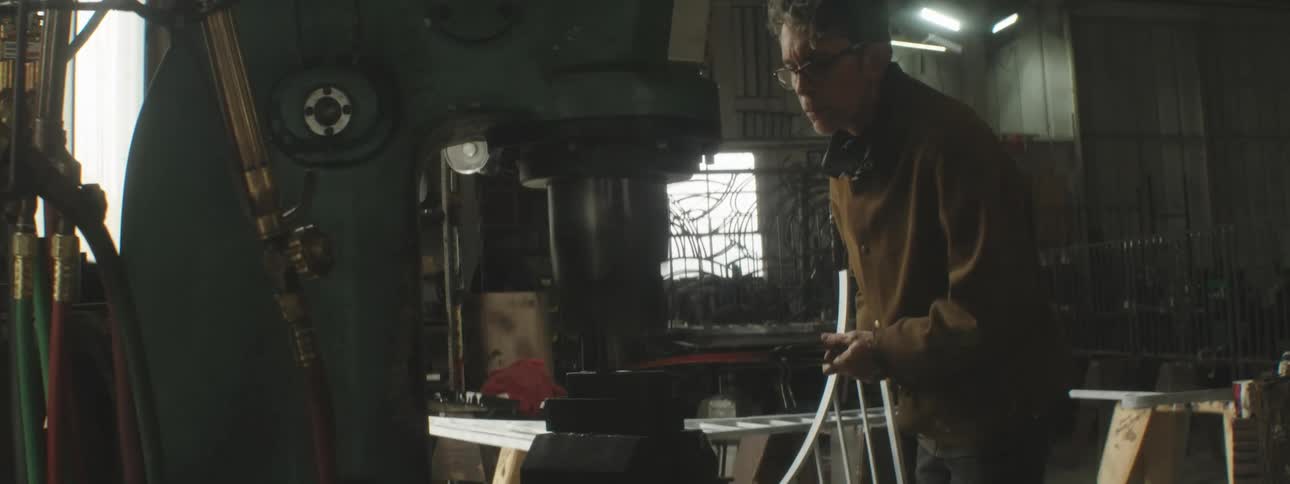 A tradesman shapes metal with a big press