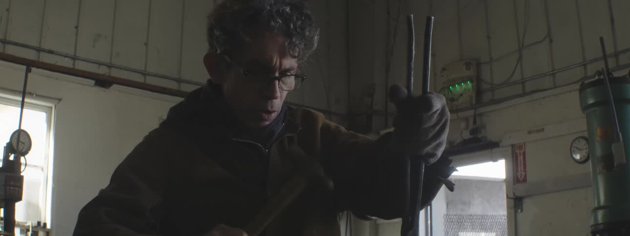 A worker uses a hammer in a shop