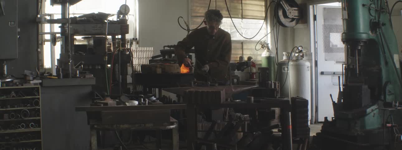 Welder man forging an iron in his factory