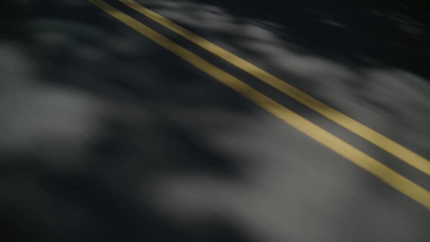 Passing the shadows of trees on a double lane road