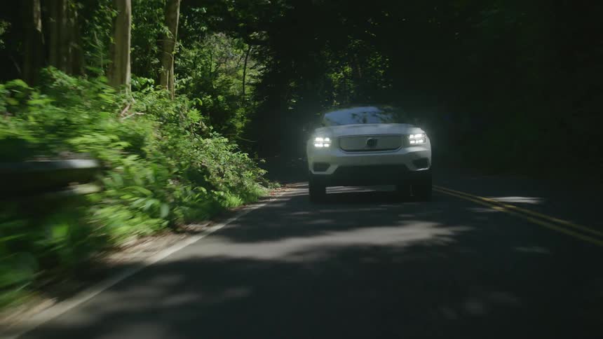 Pearl white suv vehicle traveling on a road surrounded by vegetation during the day