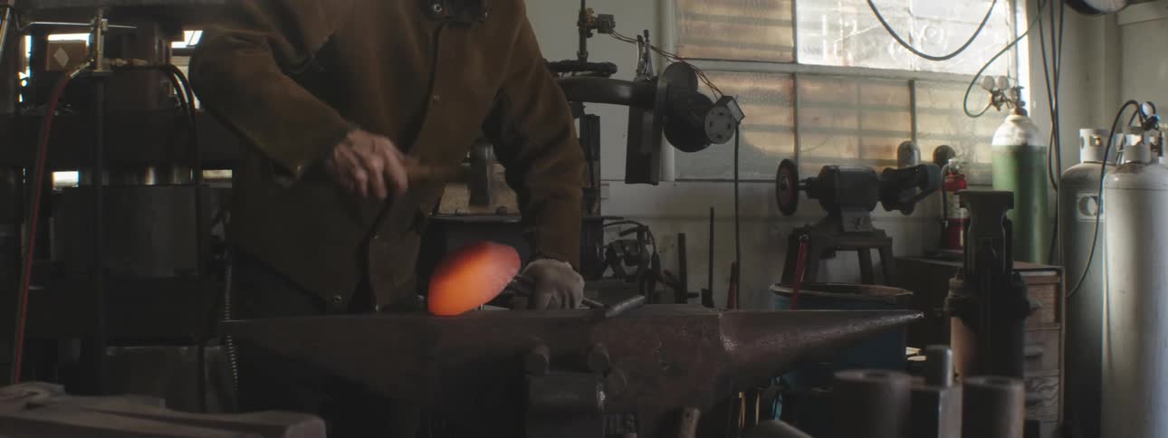 A blacksmith is hammering hot metal near the forge