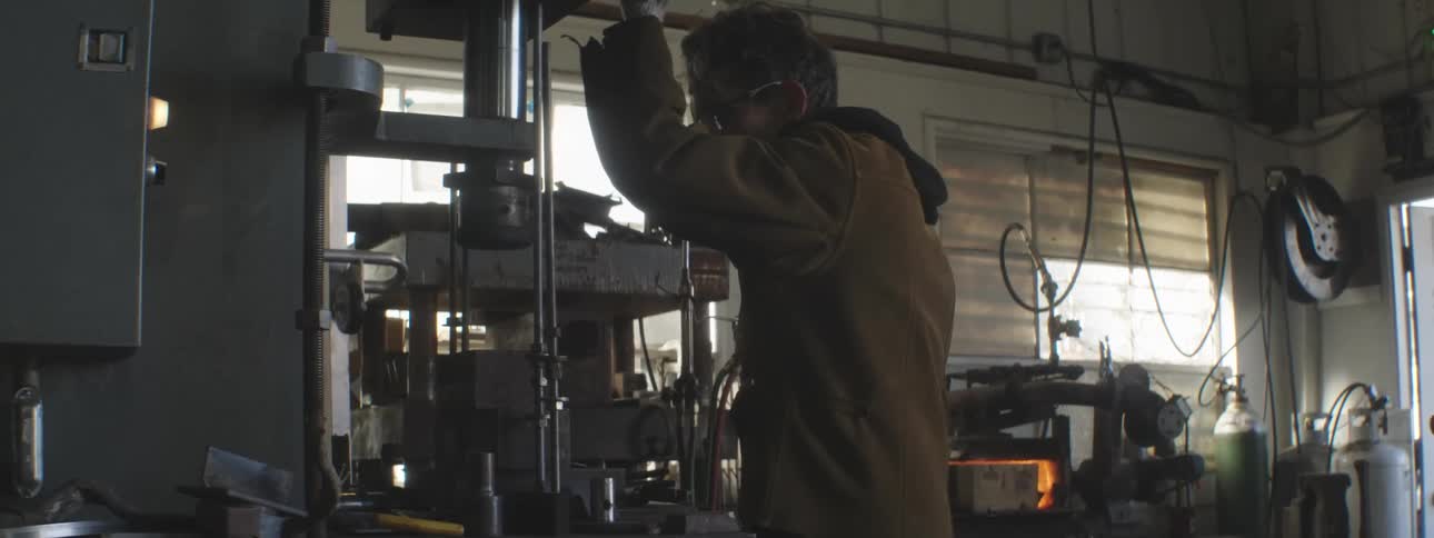 An indoor workshop scene with a person operating a machine tool