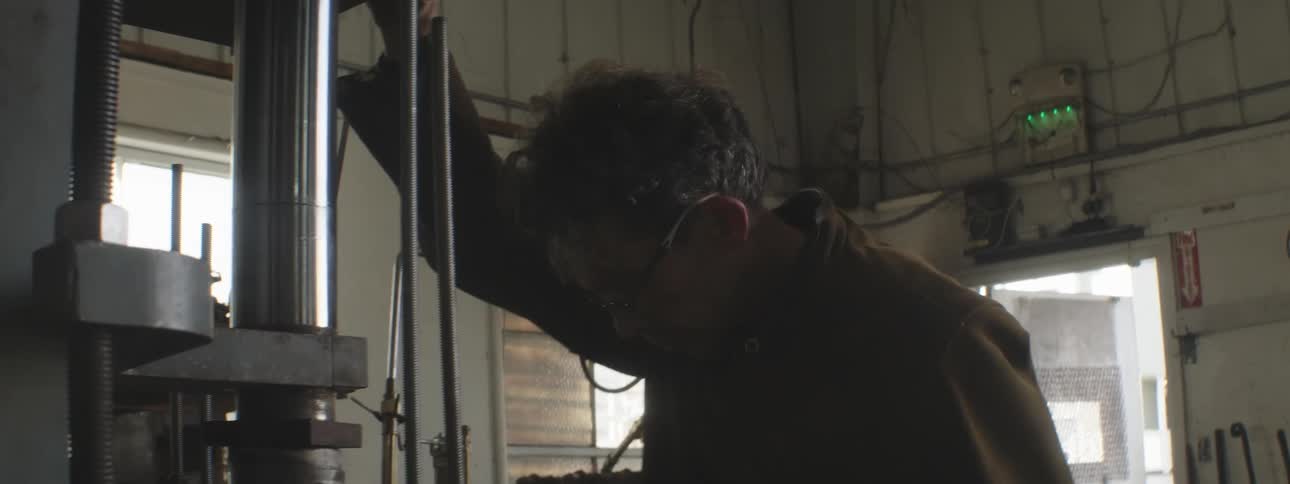 A worker uses a press in a shop