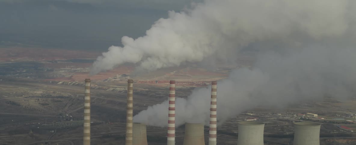 A factory with exhaust pipe blowing smokes in the air