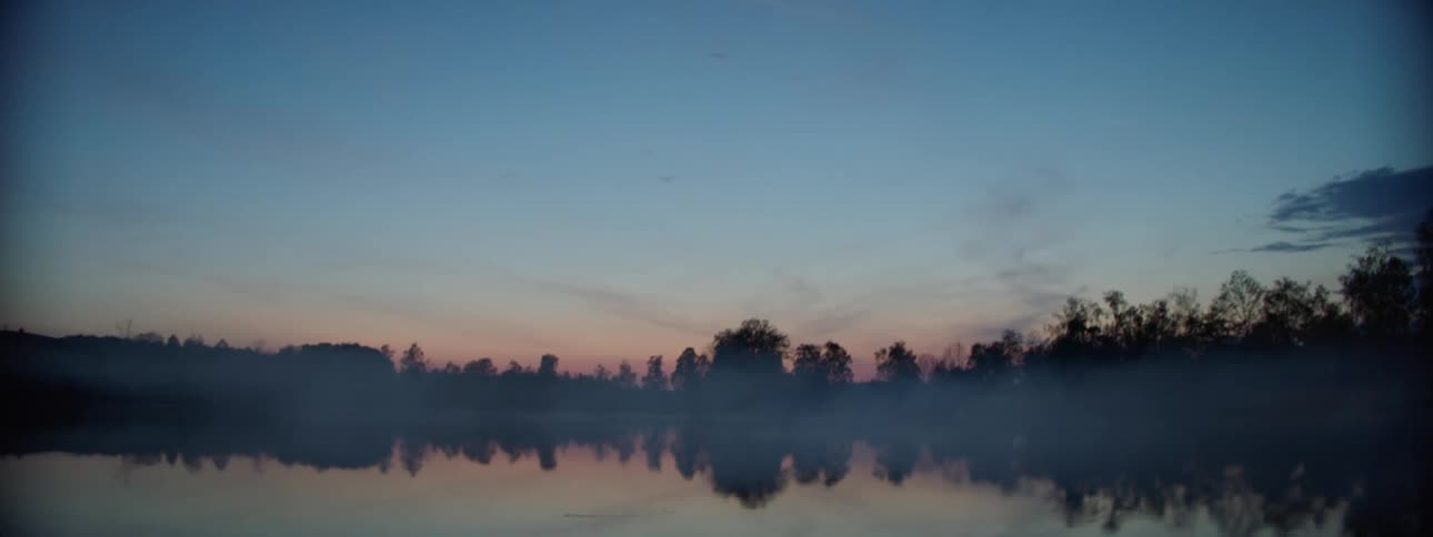 A fogcovered lake in the morning presents a serene and tranquil scene