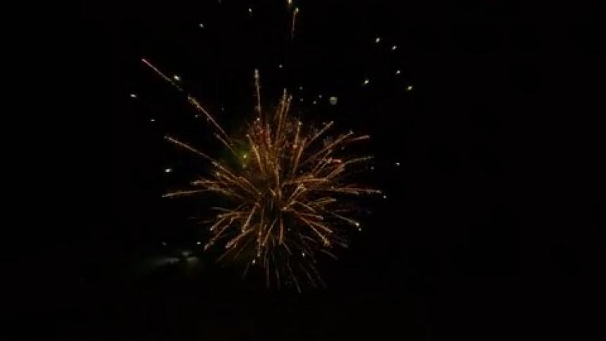 Multiple fireworks explode in the darkness of the night sky