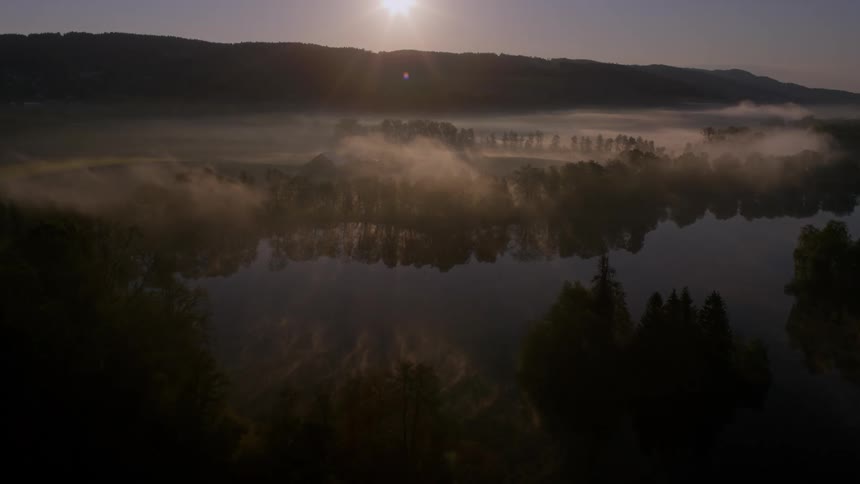 Mist above the water in front of a small mountain range at dusk
