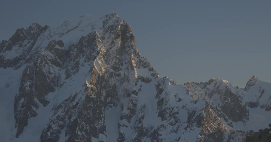 Jagged snowcovered mountain basks in soft sunlight