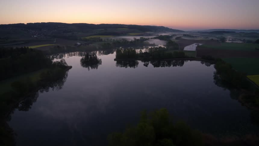 A still river at dawn surrounded by trees