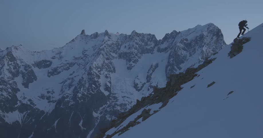 A person using equipment to climb a mountain of rocks and snow