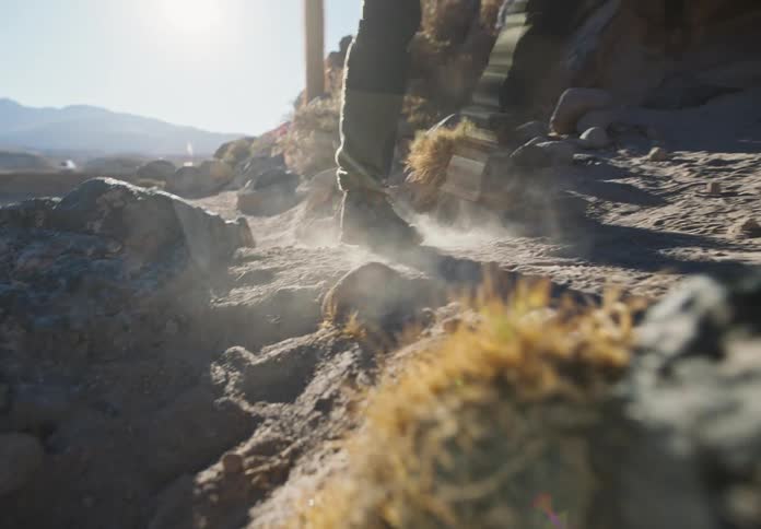 A hiker strides across a desert dirt path