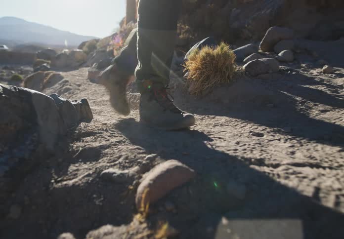 Legs of a man walking up a mountain on dry ground